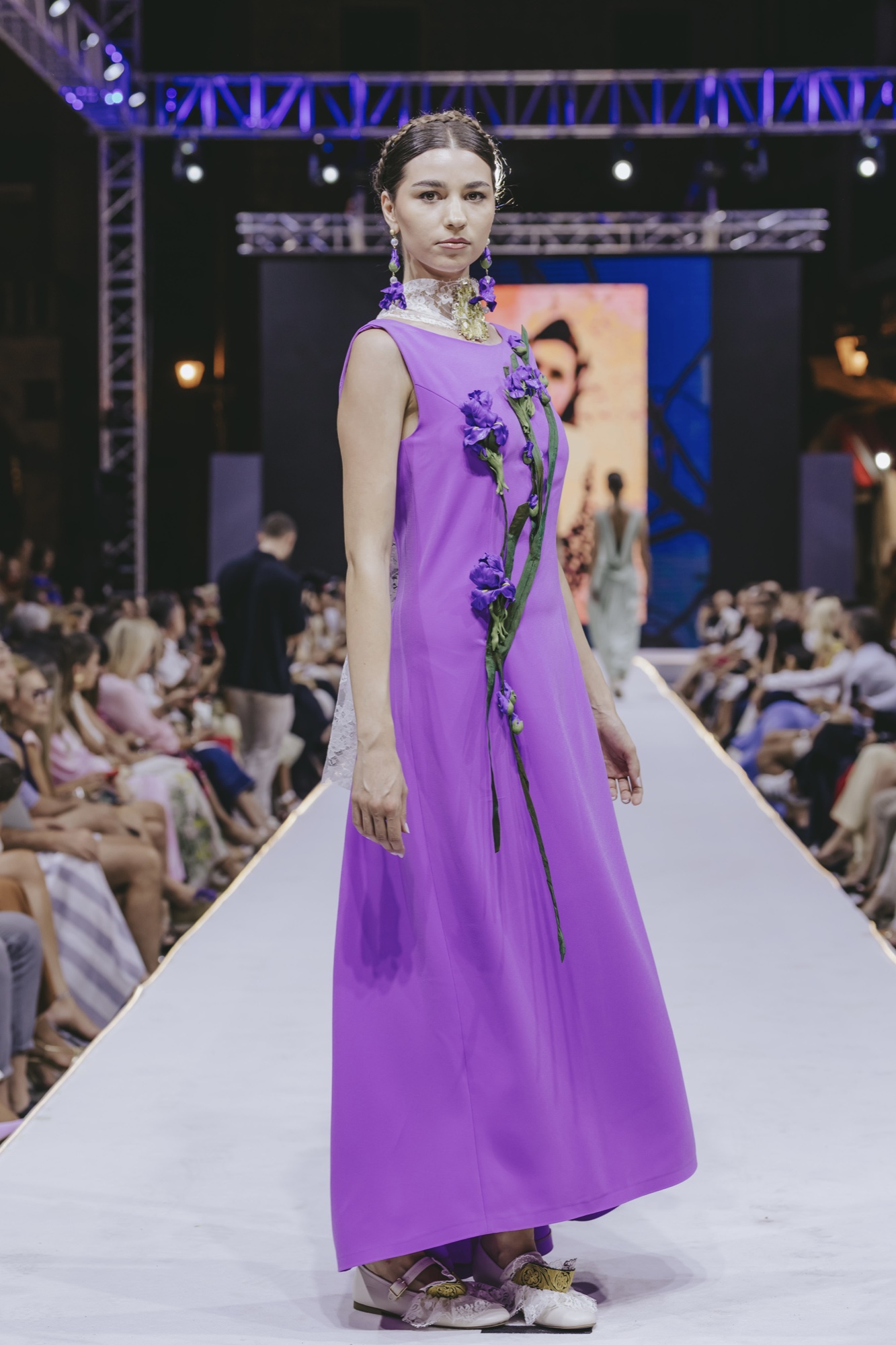 Model wearing purple iris-inspired jewellery on a runway