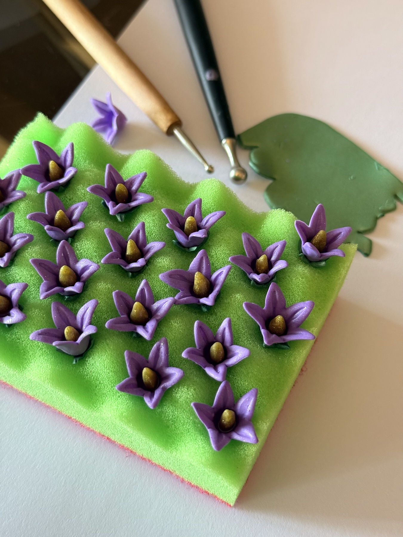 Small purple flower components being shaped by hand in the studio